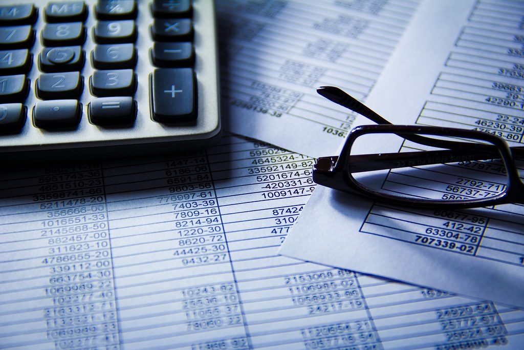 A calculator, printed chart, and financial report on a desk, representing the kind of concrete data an AI engine can quote in an answer
