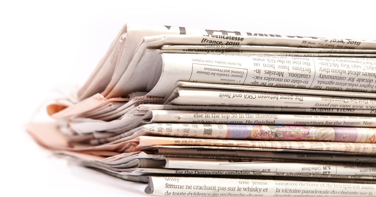 A stack of folded international newspapers on a white background, representing earned media coverage