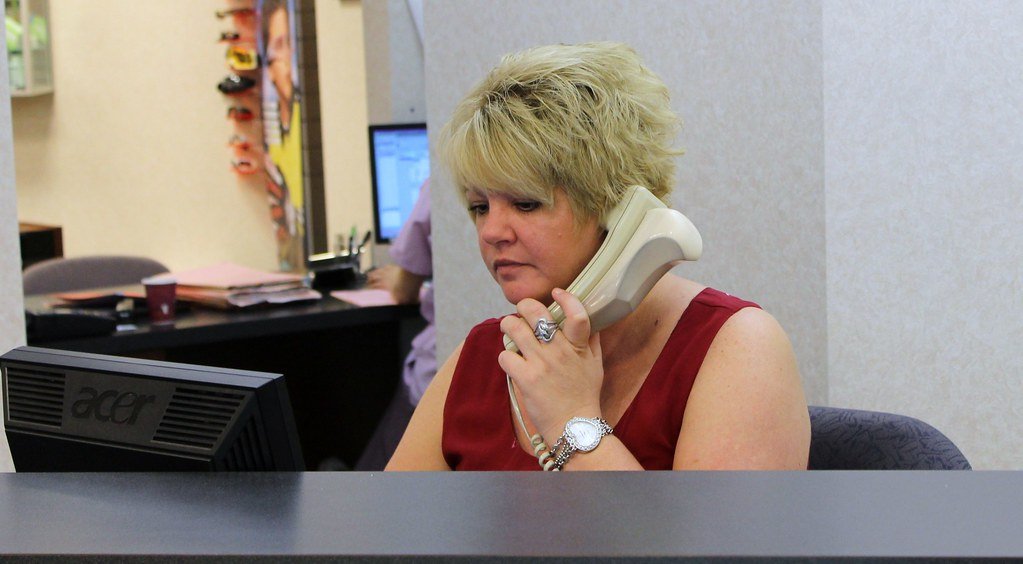 A front-desk employee at a local business answering a desk phone